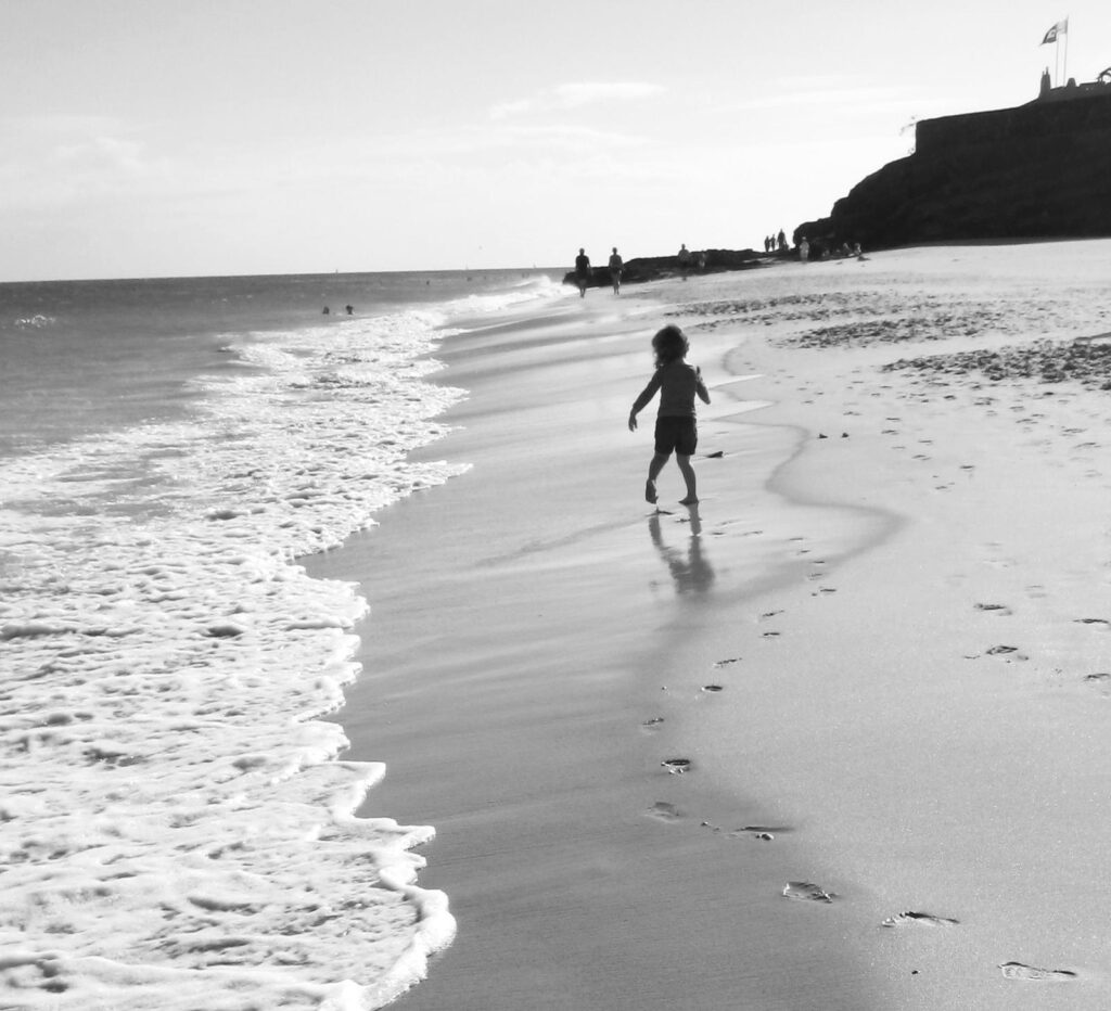 enfant marchant au bord de la plage laisse ses empreintes dans le sable noir et blanc photo